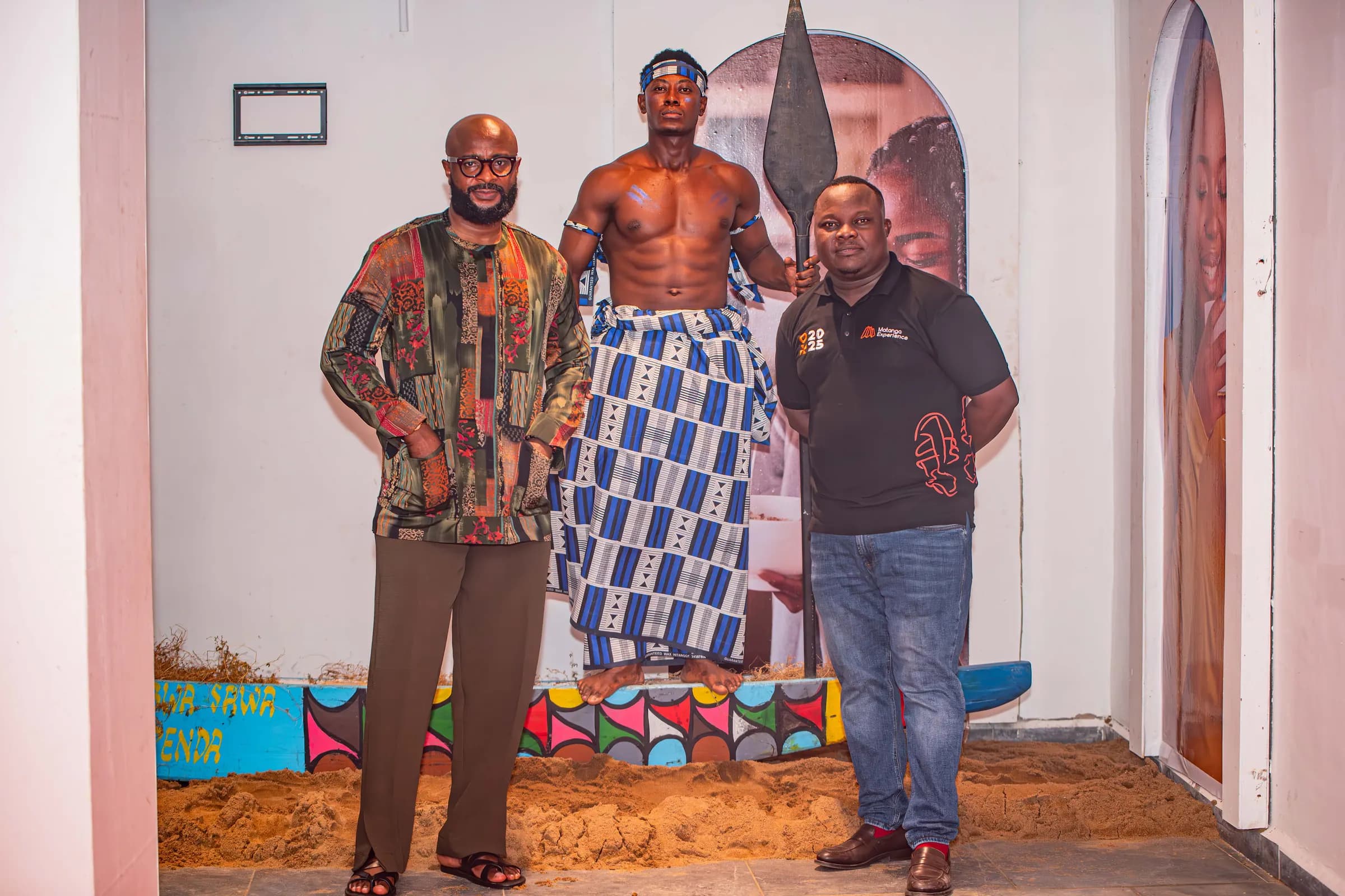 Un artiste en tenue traditionnelle pose avec deux invités.